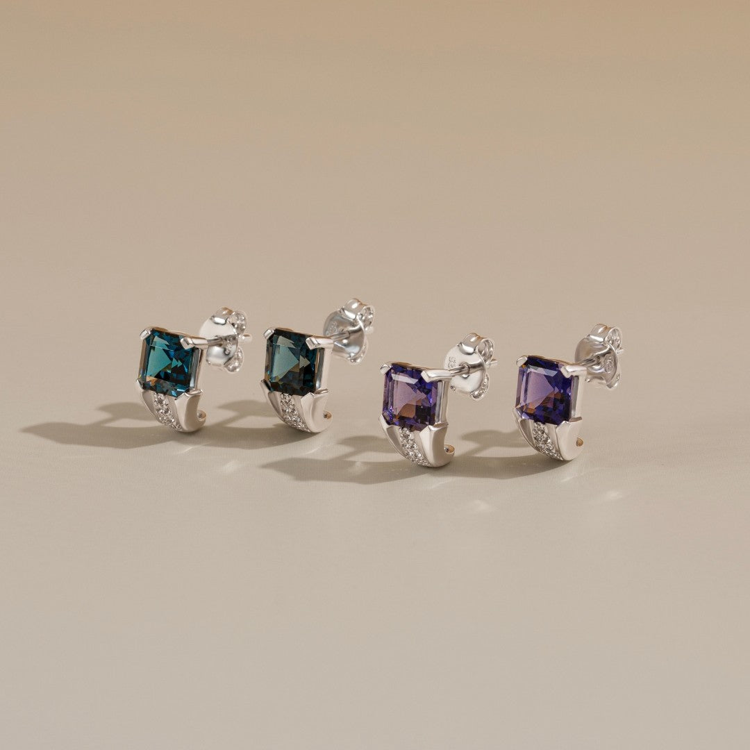 Le Petite Folie: Iolite Emerald Cut 4-Prong Ear Huggie Studs with White Topaz Accents in Rhodium Plated 925 Silver
