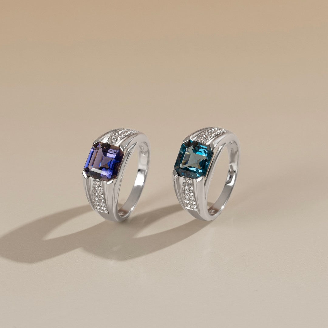 Le Petite Folie: London Blue Topaz Emerald Cut 4-Prong Band Ring with White Topaz Accents in Rhodium Plated 925 Silver