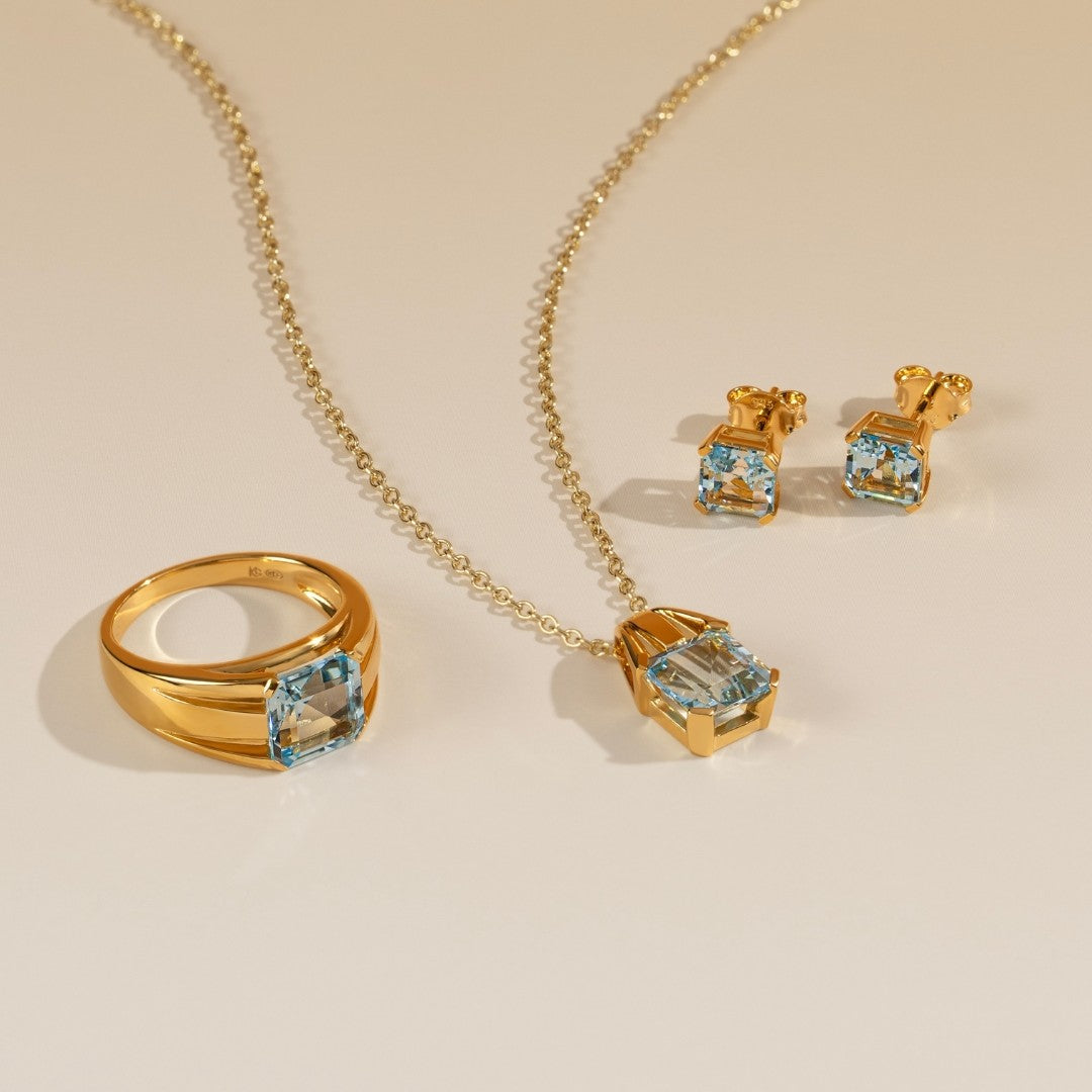 Le Petite Folie: Light Blue Topaz Princess Cut 4-Prong Stud Earrings in Gold Plated 925 Sterling Silver